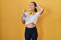 Young south asian woman wearing sportswear drinking water smiling confident touching hair with hand up gesture, posing attractive Royalty Free Stock Photo