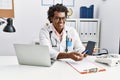 Young south east man wearing doctor uniform showing app medical smartphone at clinic