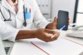 Young south east man wearing doctor uniform showing app medical smartphone at clinic