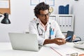 Young south east man wearing doctor uniform showing app medical smartphone at clinic