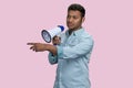 Young southasian man speaking in megaphone and pointing at something. Royalty Free Stock Photo