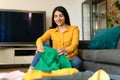 Young spanish lady packing suitcase for vacation, sitting near suitcase, preparing for travel in living room at home