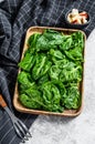 Young spinach leaves in a wooden bowl with goat cheese. Gray background. Top view