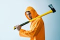 Young spooky man in orange raincoat holding big axe