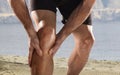 Young sport man with athletic legs holding knee in pain suffering muscle injury running