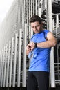 Young sport man checking time on chrono timer runners watch holding water bottle after training session Royalty Free Stock Photo