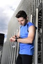 Young sport man checking time on chrono timer runners watch holding water bottle after training session Royalty Free Stock Photo