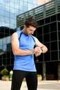 Young sport man checking time on chrono timer runners watch holding water bottle after training session Royalty Free Stock Photo