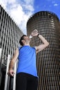 Young sport man drinking water bottle after running training session in business district Royalty Free Stock Photo