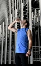 Young sport man drinking water bottle after running training session in business district Royalty Free Stock Photo