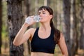 Young Sport Woman Drinking Water During Running in Beautiful Wild Pine Forest. Active Lifestyle Concept. Royalty Free Stock Photo