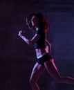 Young sport woman running jogging in gyn in blue and pink neon light on dark wall Royalty Free Stock Photo