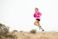 Young sport woman running off road trail dirty road with dry desert landscape background training hard Royalty Free Stock Photo