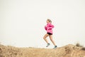 Young sport woman running off road trail dirty road with dry desert landscape background training hard Royalty Free Stock Photo