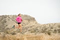 Young sport woman running off road trail dirty road with dry desert landscape background training hard Royalty Free Stock Photo