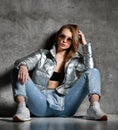 Young sport woman after workout exercise sitting under snow in silver thin down puffer jacket blue jeans Royalty Free Stock Photo