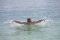 Young sporting man swims in the sea butterfly stroke style