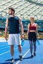 young sportive couple with bottles of water relaxing on running track