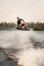 young sportive guy effectively jumps on wakeboard over the water Royalty Free Stock Photo