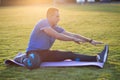 Young sportive man doing stretching exercises before running in morning field outdoors Royalty Free Stock Photo