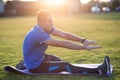 Young sportive man doing stretching exercises before running in morning field outdoors Royalty Free Stock Photo