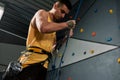 Young sportive man, rock climber holding rope, ready for training on the artificial climbing wall. Concept of sport life Royalty Free Stock Photo