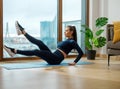 Young sportive woman does abdominal exercises on balcony