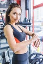 young sportive woman checking fitness tracker at gym and looking Royalty Free Stock Photo