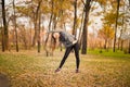 Young sportive woman doing exercises in autumn. Sportswoman stretching her body Royalty Free Stock Photo