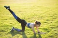 Young sportive woman doing fitness exercises on green grass in warm summer day outdoors Royalty Free Stock Photo