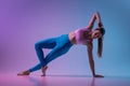 Young sportive woman training isolated on gradient studio background in neon light. athletic and graceful