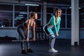 Young sports girl does deadlift with a barbell in the gym under the supervision of a trainer. Female trainer teaches