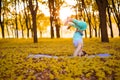 A young sports girl practices yoga in a quiet green forest in autumn at sunset, in a yoga asana pose. Meditation and oneness with Royalty Free Stock Photo