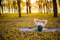 A young sports girl practices yoga in a quiet green forest in autumn at sunset, in a yoga asana pose. Meditation and oneness with