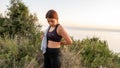 Young sports girl putting on after exercise by the sea over huge cliffs at sunset. She wears tights and sports bra Royalty Free Stock Photo