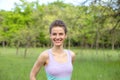 A young sports girl running in a quit green summer forest. Sport and wellness