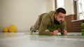 Young sports man doing elbow plank exercise in empty gym with yellow gym balls behind him all in khaki color track suit Royalty Free Stock Photo