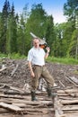 The young sports man in a light shirt green trousers and rubber boots works in the wood with a petrolsaw Royalty Free Stock Photo