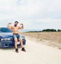 Young sports man posing near the blue sports car on the beach Royalty Free Stock Photo