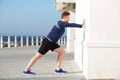 Young sports man pushing against wall