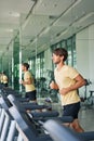 Young sports man running on a treadmill at gym doing workout Royalty Free Stock Photo