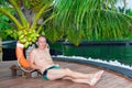 Young sports man under palm tree at pool. Maldives Royalty Free Stock Photo