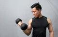 Young sports man working out with dumbbells on gray background. Closeup of a muscular young man lifting weights Royalty Free Stock Photo