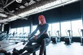 Young sports model woman working out and doing exercise on the machine in the gym