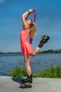 young sports trainer with beautiful legs in a pink dress jumps on spring shoes near the lake. Royalty Free Stock Photo