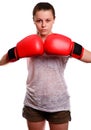 A young sports woman-boxer poses to the camera in red boxing gloves. She concentrates and standing in the battle rack