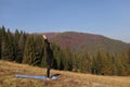 Young sports woman doing yoga exercise on the mountains and sky background in the autumn Royalty Free Stock Photo