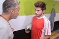 young sportsman being reprimanded by coach in changing room Royalty Free Stock Photo