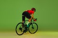 Young sportsman, cyclist on bicycle in sports uniform and protective helmet training isolated on green background