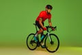 Young sportsman, cyclist on bicycle in sports uniform and protective helmet training isolated on green background